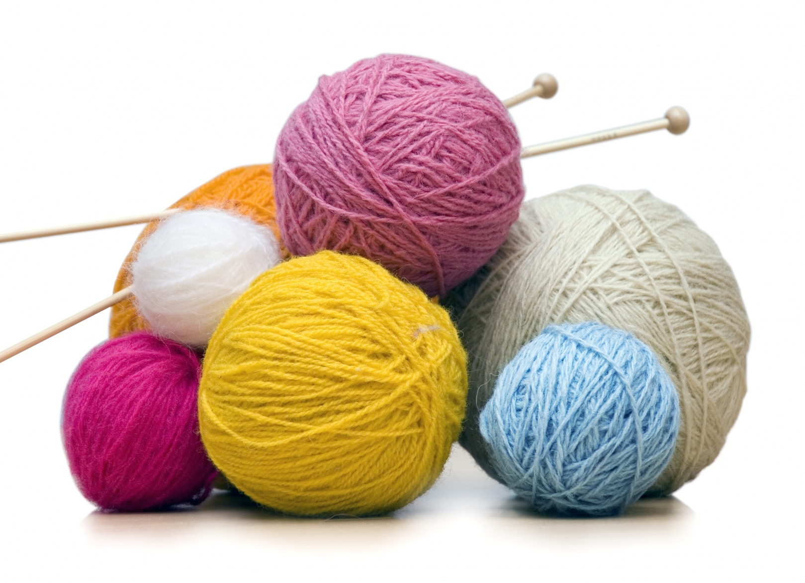 alt="balls of yarn in various colors & sizes with a pair of knitting needles sticking through one ball of yarn"